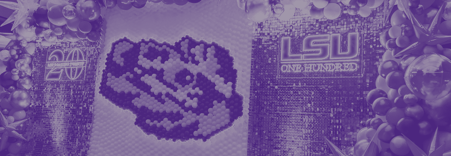 Balloon sculpture and sequin wall with signs reading “20” and “LSU One Hundred,” decorated with metallic balloons.